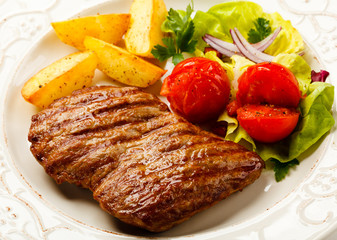 Grilled steak, baked potatoes and vegetable salad 