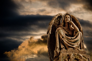 pensive angel statue over dramatic sky