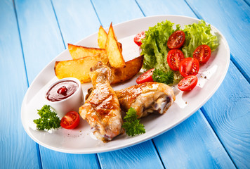 Grilled chicken legs with chips and vegetables 