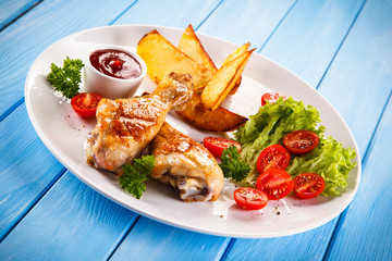Grilled chicken legs with chips and vegetables 