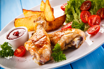 Grilled chicken legs with chips and vegetables 