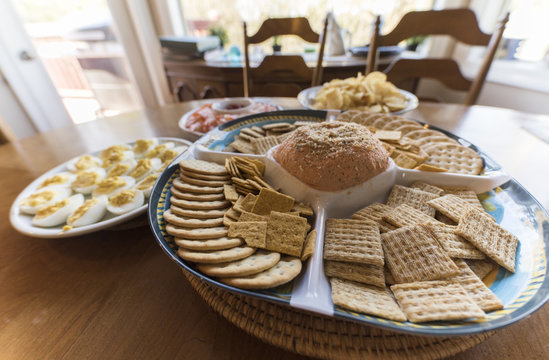 Table Full Of Snack Plates And Appetizers, Crackers, Chips, Salmon Dip, Cocktail Shrimp, And Deviled Eggs