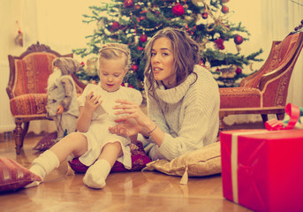 Mother and daughter in front of Christmas tree, opening presents