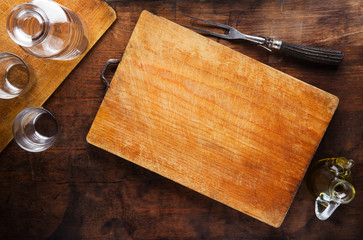 cutting board on vintage wooden table, carafe with glasses, knif