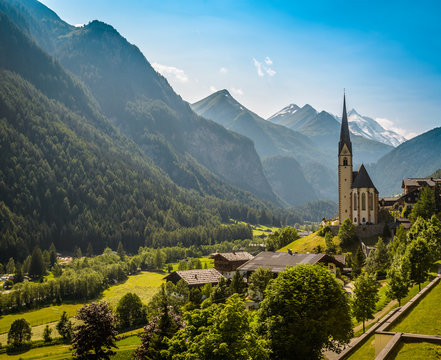 Rural landscape of Heiligenblut with St Vincent Church in Carynthia and Grossglockner (3797 m. elevation) highest mountain from Austria in background.