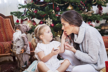 Mother and daughter in front of Christmas tree, opening presents