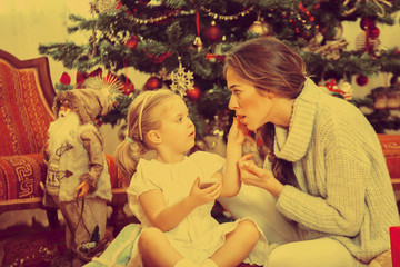 Mother and daughter in front of Christmas tree, opening presents