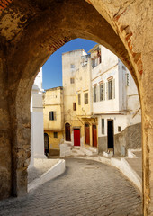 Naklejka premium Narrow street in Tangier, view through the town wall gate, Morocco