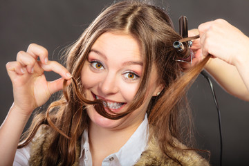 Stylist curling hair for young woman.