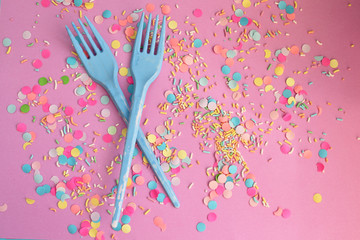 Blue fork on pink confetti background - party time