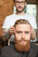 Skillful male barber is serving his client