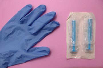 Sterile surgical glove, syringe and needle on blue background - medicine concept