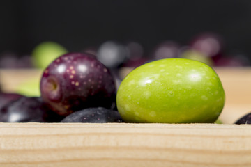 Green olive beside other ones with different shades of color and ripening. Preparing seasoned table olives