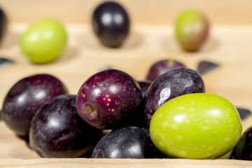 Green olives beside other ones with different shades of color and ripening. Preparing seasoned table olives