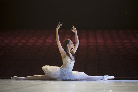 Young ballerina in theater dancing in costume.