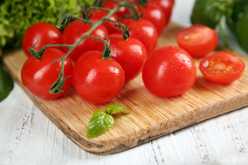 Cherry tomatoes with basil on wooden table close up