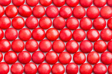 Close up neatly arranged red milk chocolate candies crisp shell