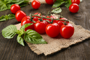 Fresh tomatoes with basil on wooden table close up