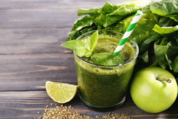 Green healthy juice with fruits and herbs on wooden table close up