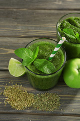 Green healthy juice with fruits and herbs on wooden table close up