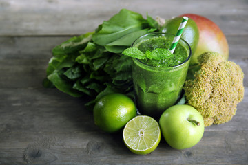 Green healthy juice with fruits and vegetables on wooden table close up