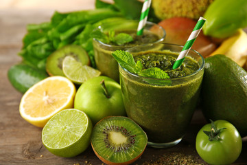 Green healthy juice with fruits and vegetables on wooden table close up