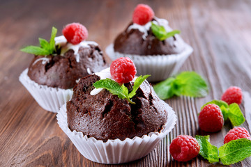 Delicious chocolate cupcakes with berries and fresh mint on wooden table close up