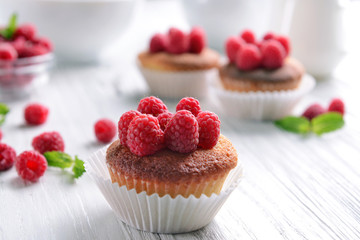 Delicious cupcakes with berries and fresh mint on wooden table close up