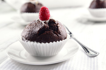Delicious chocolate cupcake with raspberry on table close up
