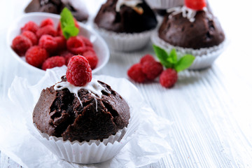 Delicious chocolate cupcakes with berries and fresh mint on table close up