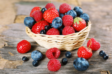 Sweet tasty berries in basket on wooden table close up