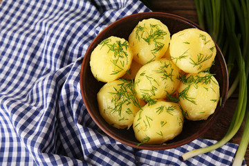 Boiled potatoes with greens in bowl on table close up