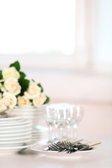 Clean plates, glasses and cutlery on white table