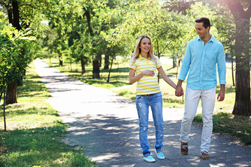 Obraz premium Young pregnant woman with husband walking in park
