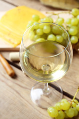 Still life of wine, grape, cheese and bread on rustic wooden background
