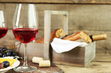 Still life of wine, grape, cheese and bread on rustic wooden background