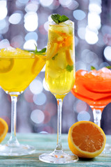 Glasses of cocktails with ice on blurred lights background
