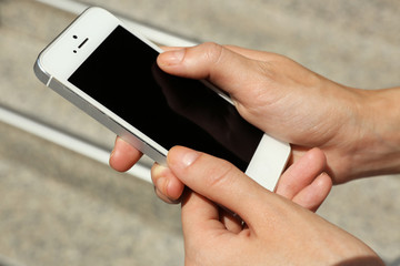 Female hands holding smart mobile phone outdoors