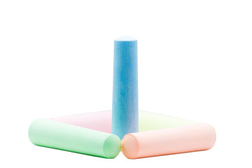 Blue colored chalk standing inside 4 colored chalks on white bac