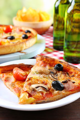 Sliced pizza served with beer on wooden table