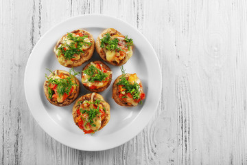 A plate with stuffed mushrooms on wooden background, top view
