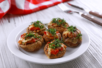 A plate with stuffed mushrooms on wooden background