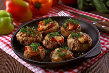 A frying pan with stuffed mushrooms on the table