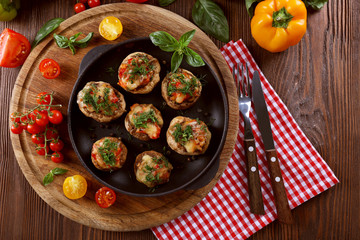 A frying pan with stuffed mushrooms and vegetables on the table, top view