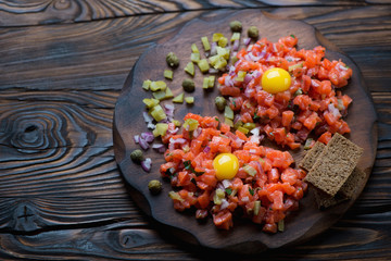 Wooden rustic chopping board with salmon tartar, studio shot