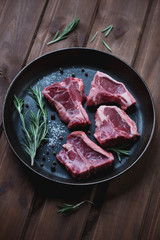 Frying pan with raw fresh T-bone lamb steaks, selective focus