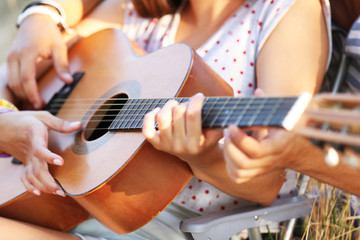 Fototapeta premium Attractive couple playing guitar, outdoors, close up