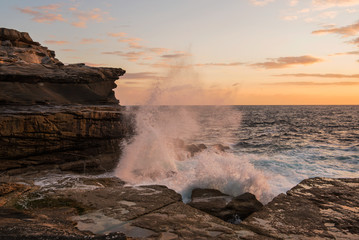 Orange crashing wave over cliffs