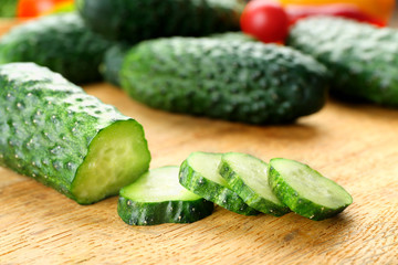 Composition of cucumbers, tomatoes and sweet peppers circles on wooden background, close up