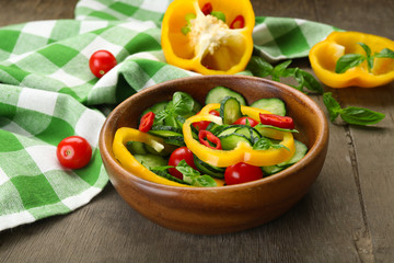 Vegetable salad with cucumbers  on wooden background decorated with green checked cotton serviette and sweet pepper